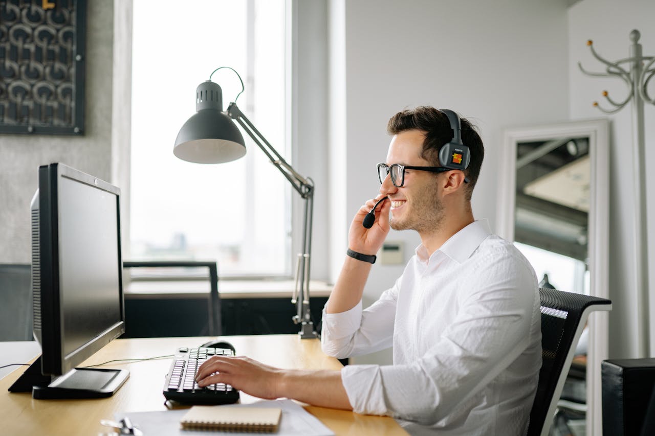 Crafting Captivating Headlines: Your awesome post title goes here Smiling man wearing headset working at computer in bright office.